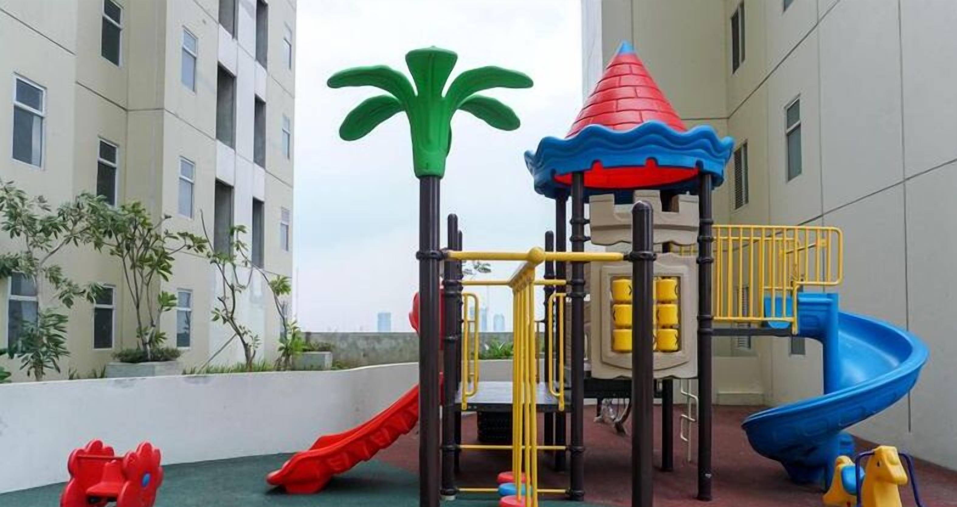 A playground with slides and climbing structures, surrounded by apartment buildings.