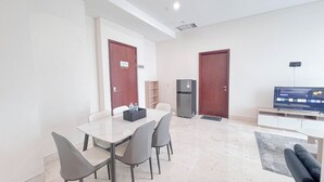 Uma sala de estar moderna com área de jantar, geladeira e televisão.