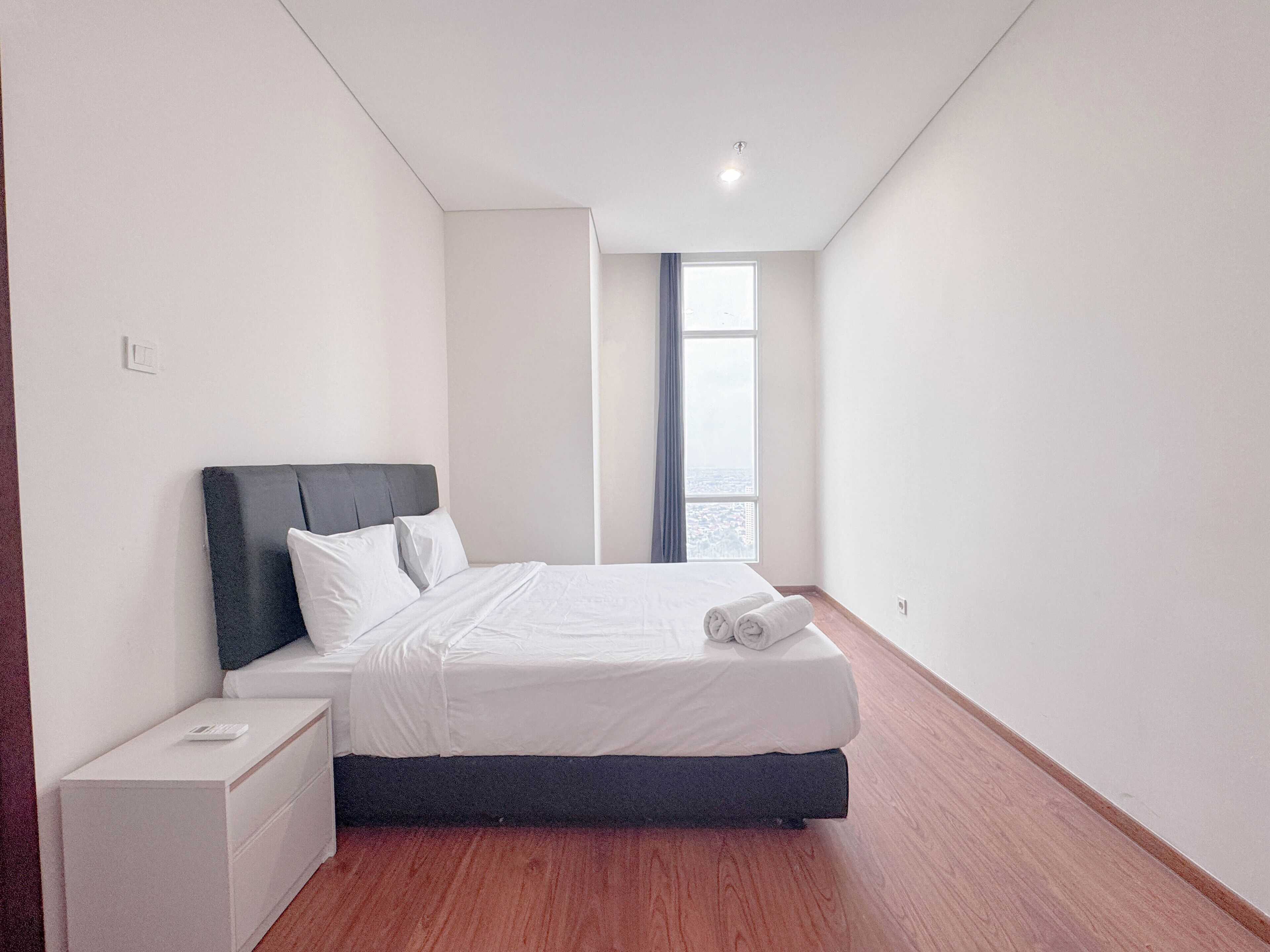 Un dormitorio moderno con cama, mesita de noche y ventana con vistas.