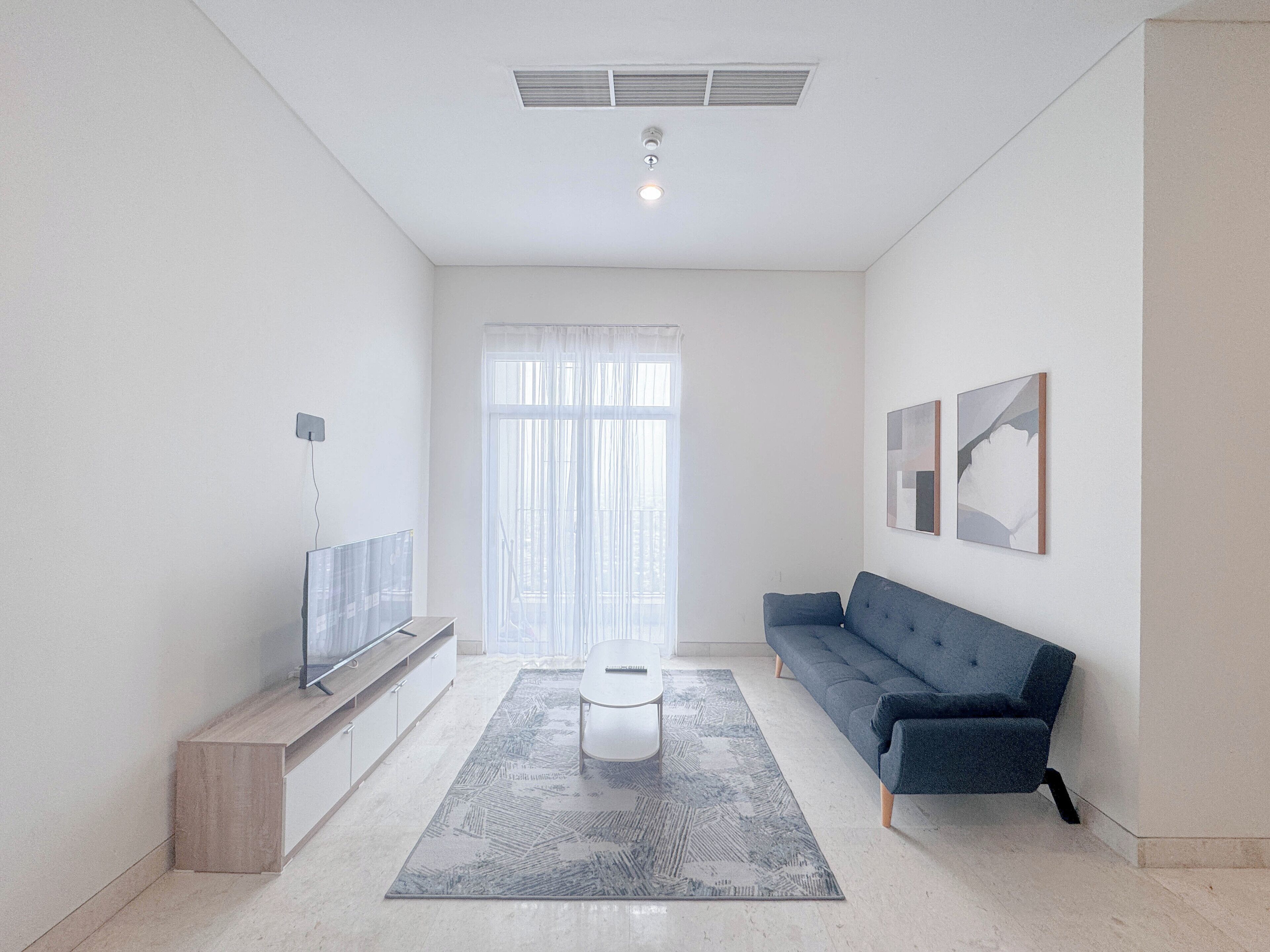 Una sala de estar moderna con un sofá, una mesa de centro, un televisor y obras de arte en la pared.