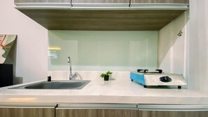 A kitchen with a sink, a small plant, and a portable stove. - Spacious And Relaxing 2Br Apartment At Corner Vittoria Residence (Jakarta)