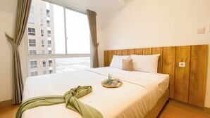 A hotel room with a large bed, wooden headboard, and a window with curtains. - Big 1Br Apartment Tokyo Riverside Pik 2 (Teluknaga)