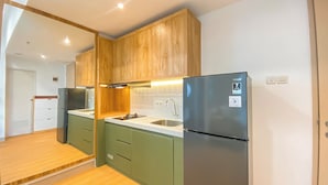 A compact kitchen with wooden cabinets, a stainless steel refrigerator, and a built-in sink. - Big 1Br Apartment Tokyo Riverside Pik 2 (Teluknaga)