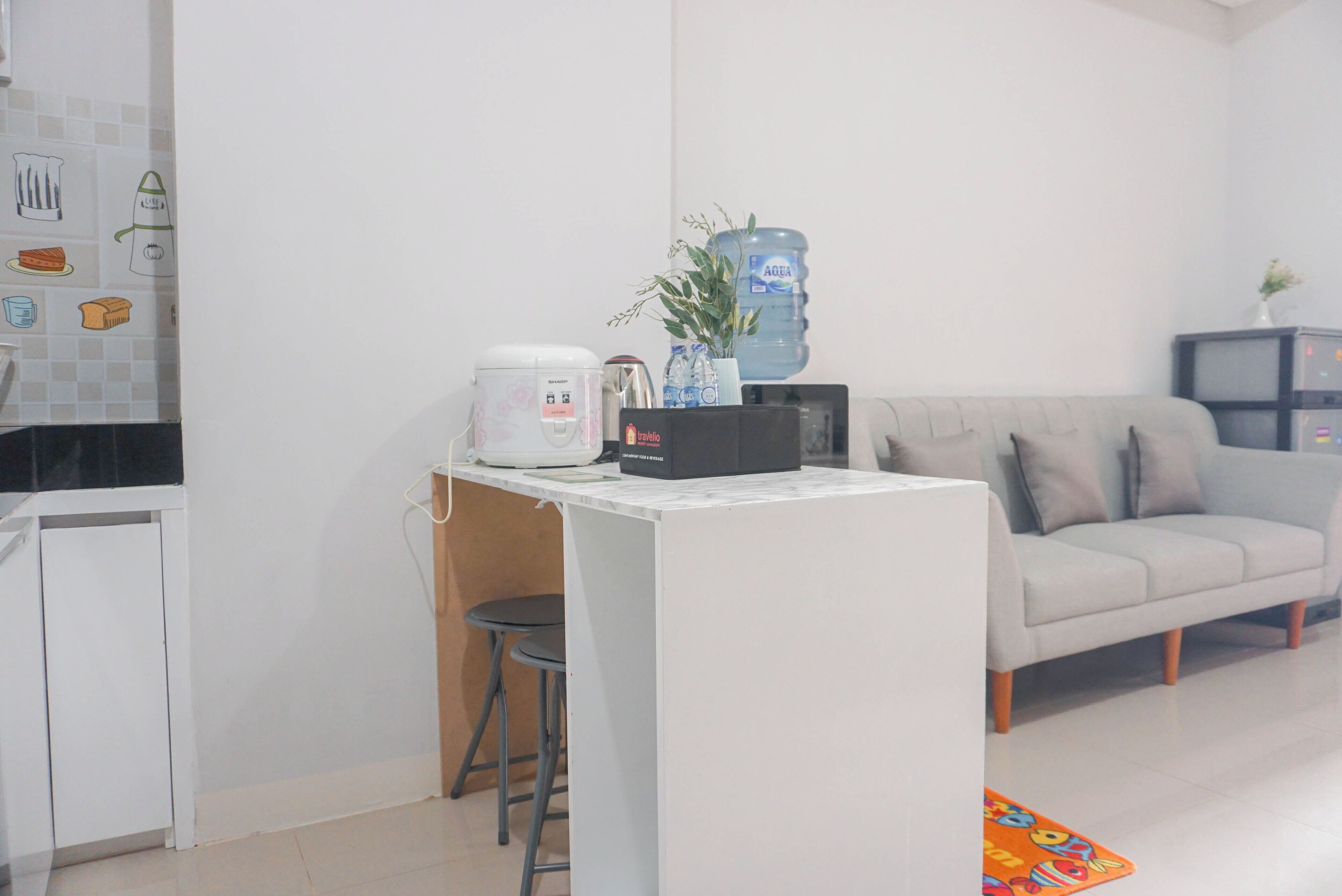 A compact living space with a kitchenette, a sofa, and a coffee machine.