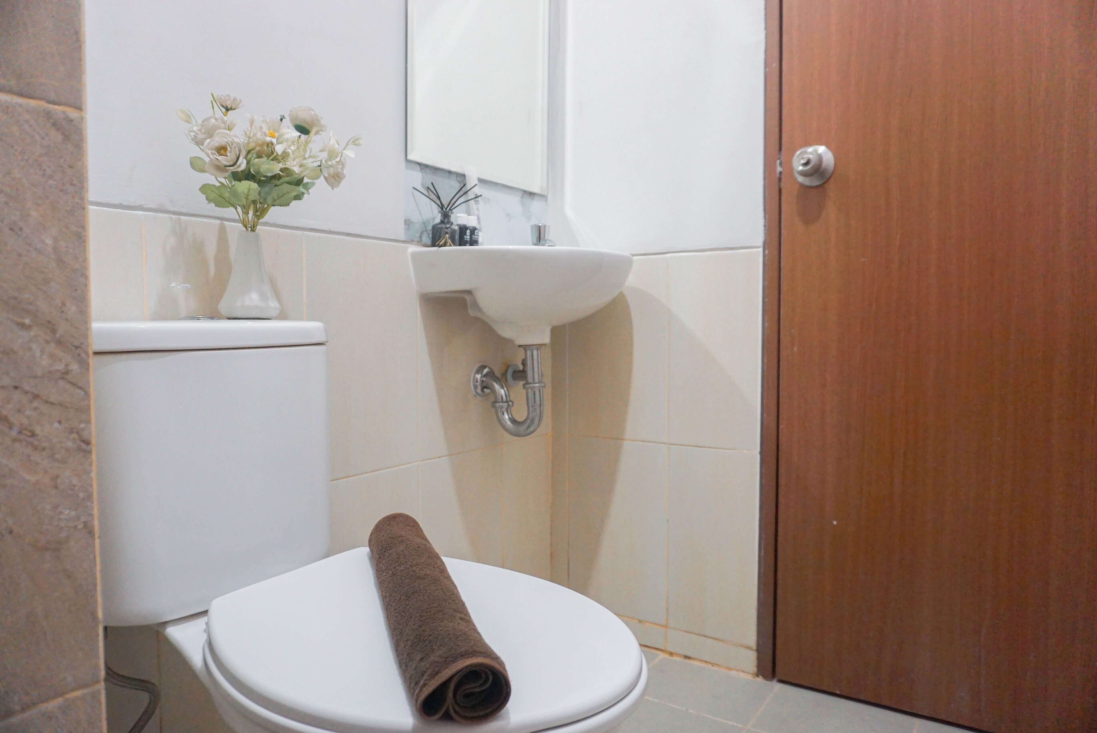 A bathroom with a toilet, sink, and a wooden door.