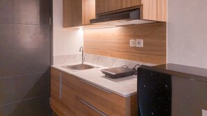 A modern kitchen with two sinks, wooden cabinets, and a built-in oven. - Highest Value Studio Room At Collins Boulevard Apartment (Tangerang)