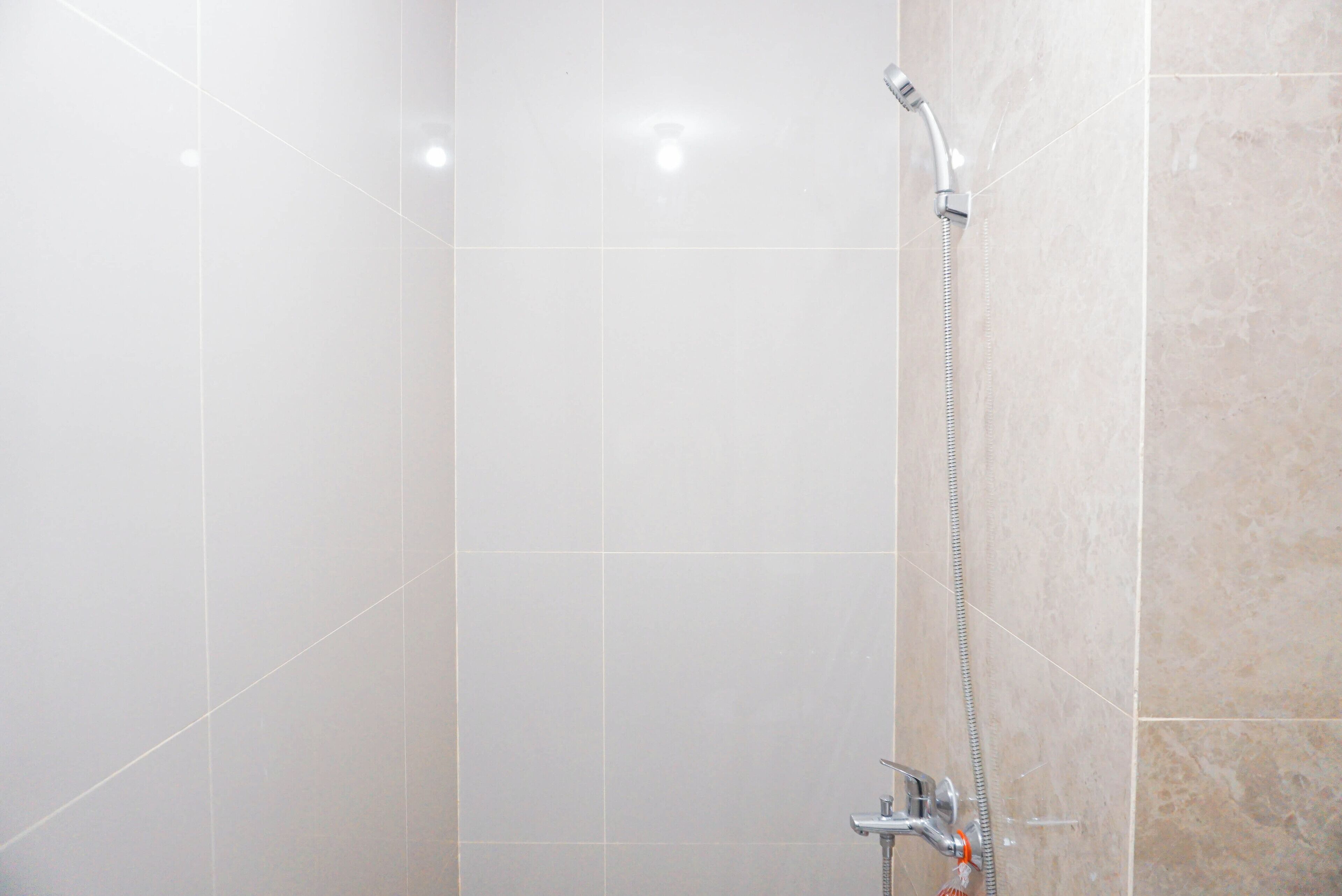 A bathroom with a shower, tiled walls, and a visible showerhead.