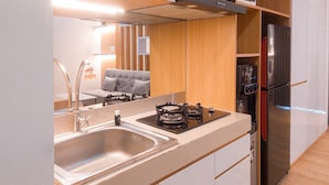 A compact kitchen with a stainless steel refrigerator, a built-in oven, and a sink. - Cozy Studio Apartment Parkland Avenue (South Tangerang)