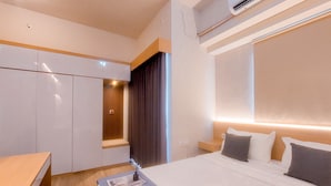 A modern hotel room with a bed, bedside table, and wardrobe. - Cozy Studio Apartment Parkland Avenue (South Tangerang)