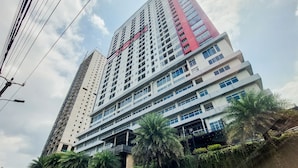A high-rise building with multiple floors, a prominent red section, and a sign that reads "DONG." - Cozy Studio Apartment Parkland Avenue (South Tangerang)