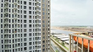 A high-rise building with multiple balconies and a view of a river and industrial area. - Comfy And Lovely 2Br Apartment Tokyo Riverside Pik 2 (Teluknaga)