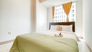 A hotel room with a bed, a window with curtains, a bedside table, and a view of buildings outside. - Comfy And Lovely 2Br Apartment Tokyo Riverside Pik 2 (Teluknaga)