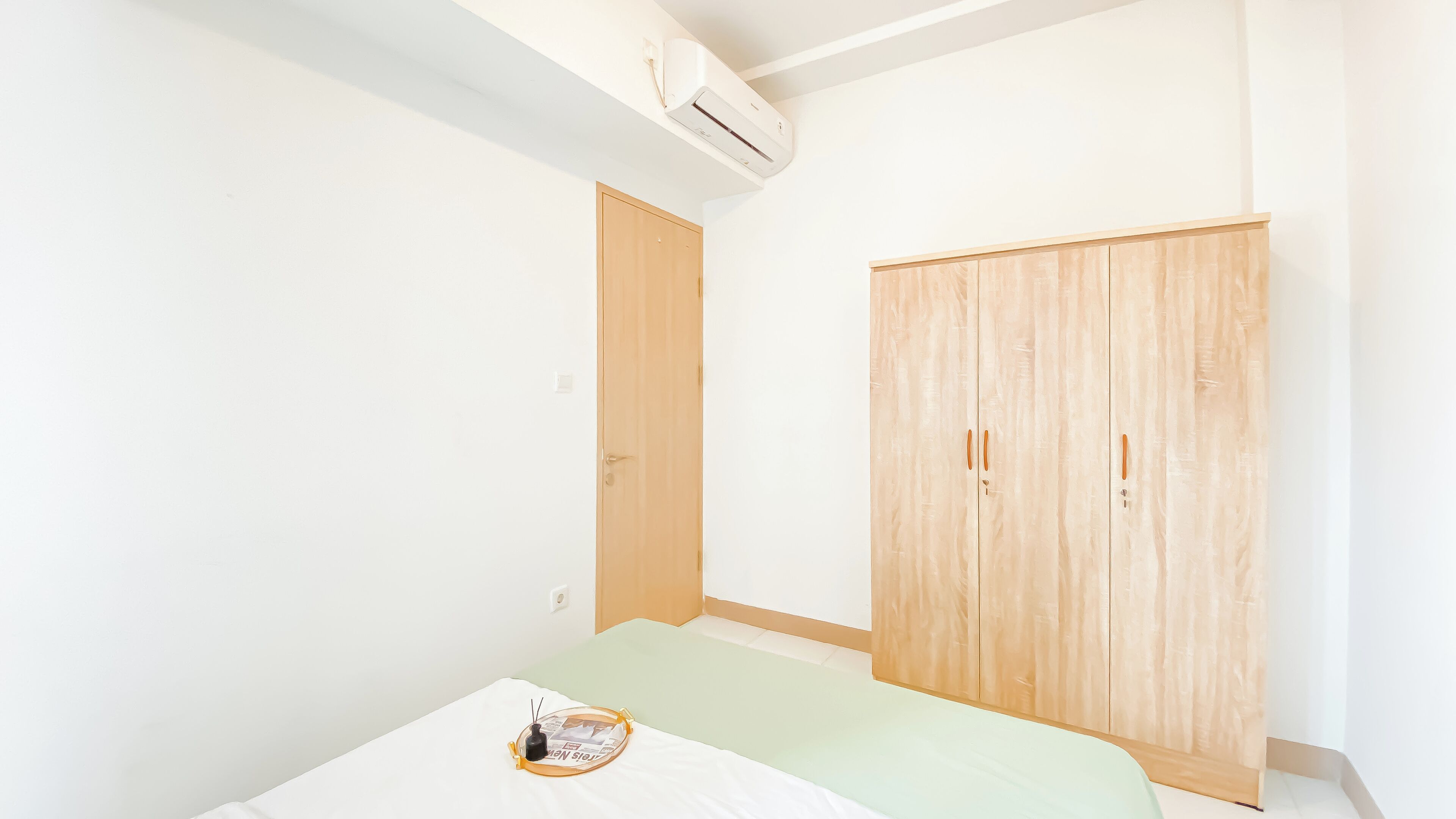 A bedroom with a bed, a wardrobe, and an air conditioning unit.