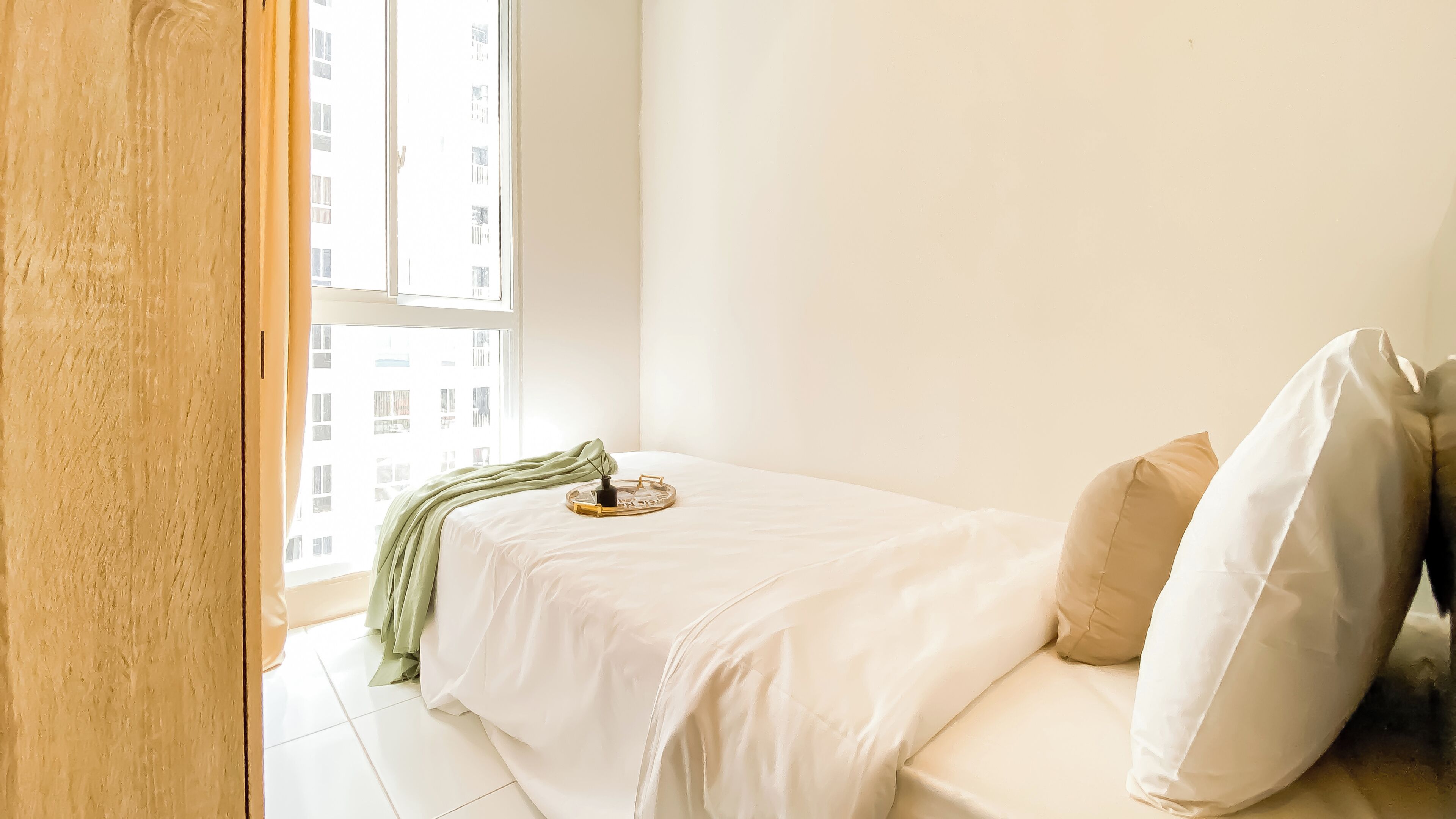 Ein schlicht eingerichtetes Schlafzimmer mit Bett, Fenster und Blick auf Gebäude.