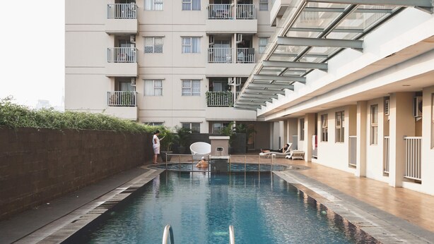 A swimming pool with a clear view of a multi-story building in the background. - Lovely 2Br Apartment At Belmont Residence Puri (Jakarta)