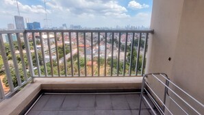A balcony with a metal railing overlooking a cityscape with buildings and greenery. - Lovely 2Br Apartment At Belmont Residence Puri (Jakarta)