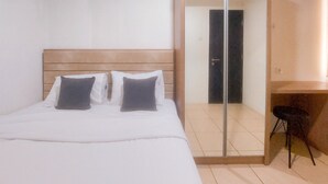A hotel room with a bed, a chair, and a door. - Lovely 2Br Apartment At Belmont Residence Puri (Jakarta)
