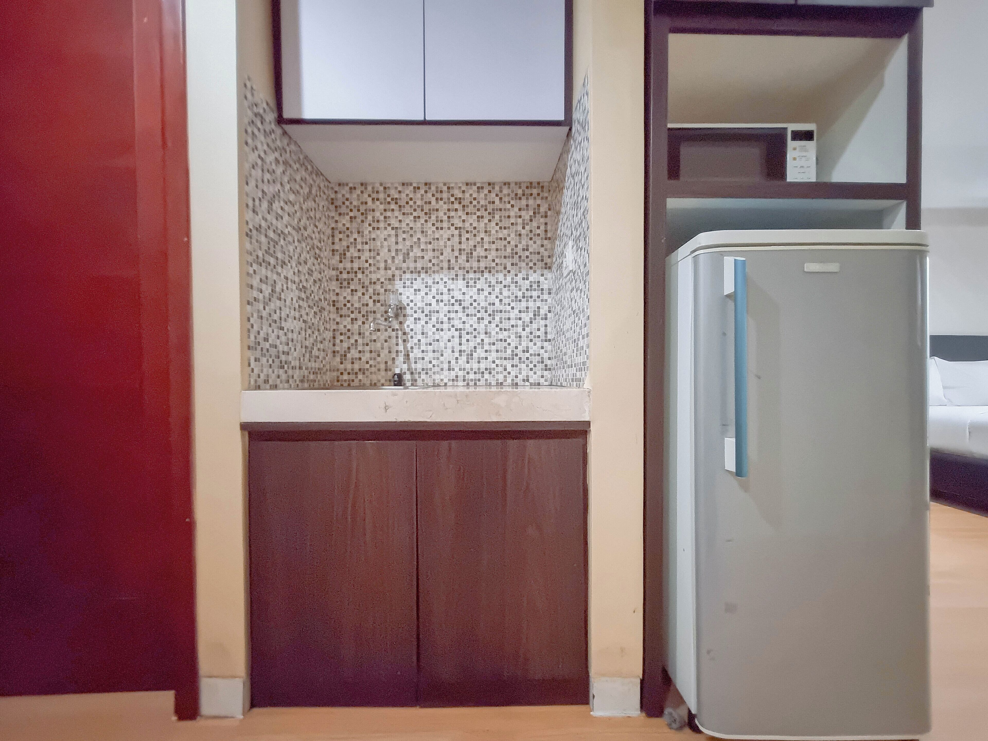 A small kitchen with a refrigerator, a microwave, and a tiled backsplash.