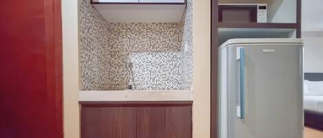 A small kitchen with a refrigerator, a microwave, and a tiled backsplash.