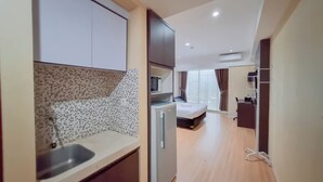 A modern hotel room with a kitchenette, a bed, and a bathroom. - Relaxing And Stylish Studio At Mataram City Apartment (Ngaglik)