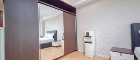 Un dormitorio con cama, mesita de noche, espejo y dispensador de agua.