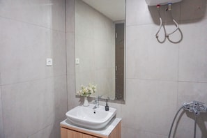 Une salle de bain avec un lavabo blanc, un miroir et une douche.