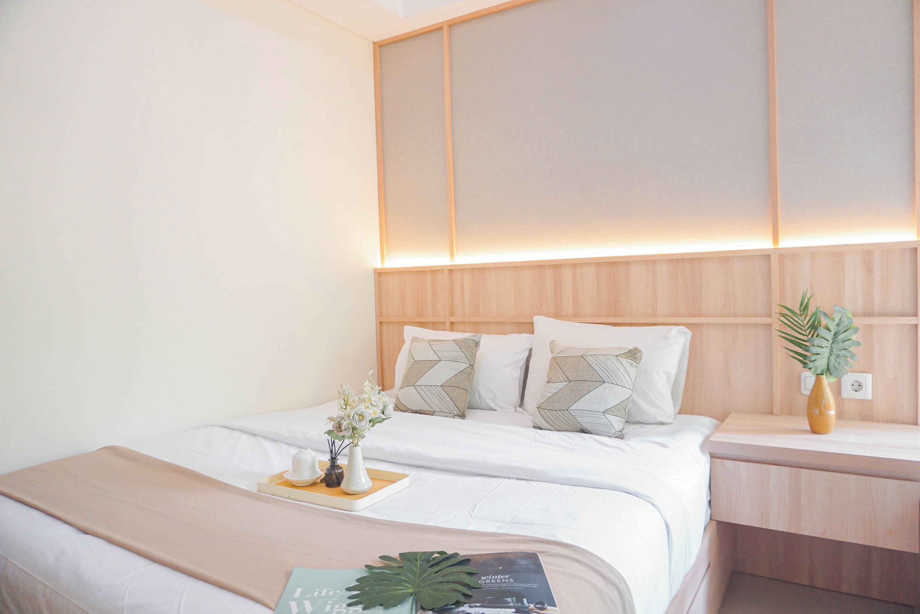 Ein ordentlich eingerichtetes Hotelzimmer mit Bett, Nachttisch und Beistelltisch.
