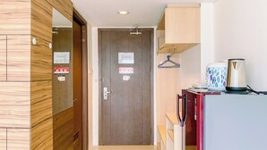 Un passadís amb una porta de fusta, un petit armari amb una tetera i un penjador.