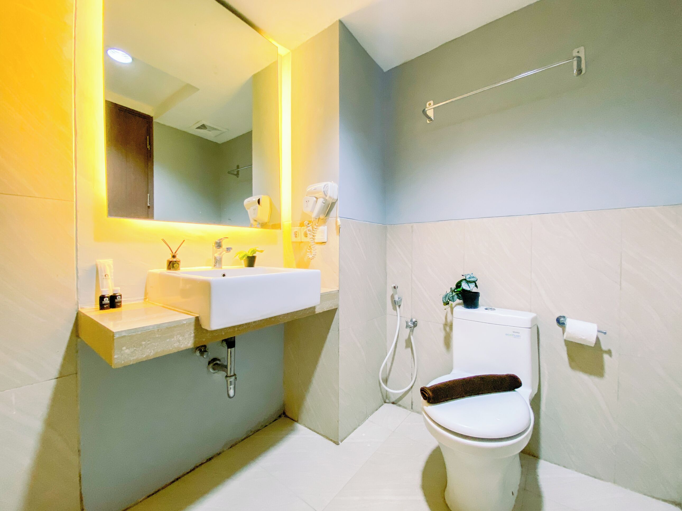 A modern bathroom with a white sink, mirror, and toilet.