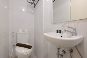 A bathroom with a toilet, sink, and mirror. - Comfy And Well Studio At Tokyo Riverside Pik 2 Apartment (Teluknaga)