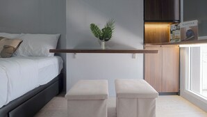 A bedroom with a bed, a bedside table, a small potted plant, and a nightstand. - Comfy And Well Studio At Tokyo Riverside Pik 2 Apartment (Teluknaga)