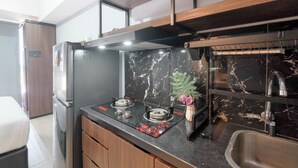 A compact kitchen with a built-in refrigerator, a gas stove, and a sink. - Comfy And Well Studio At Tokyo Riverside Pik 2 Apartment (Teluknaga)