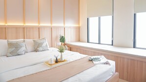 Un dormitorio moderno con una cama grande, mesitas de noche, un ventanal con vistas e un cabecero con iluminación integrada.