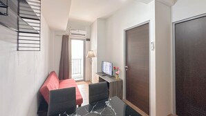 Et hotelværelse med en seng, et skrivebord med computer, et fjernsyn og en trappe.