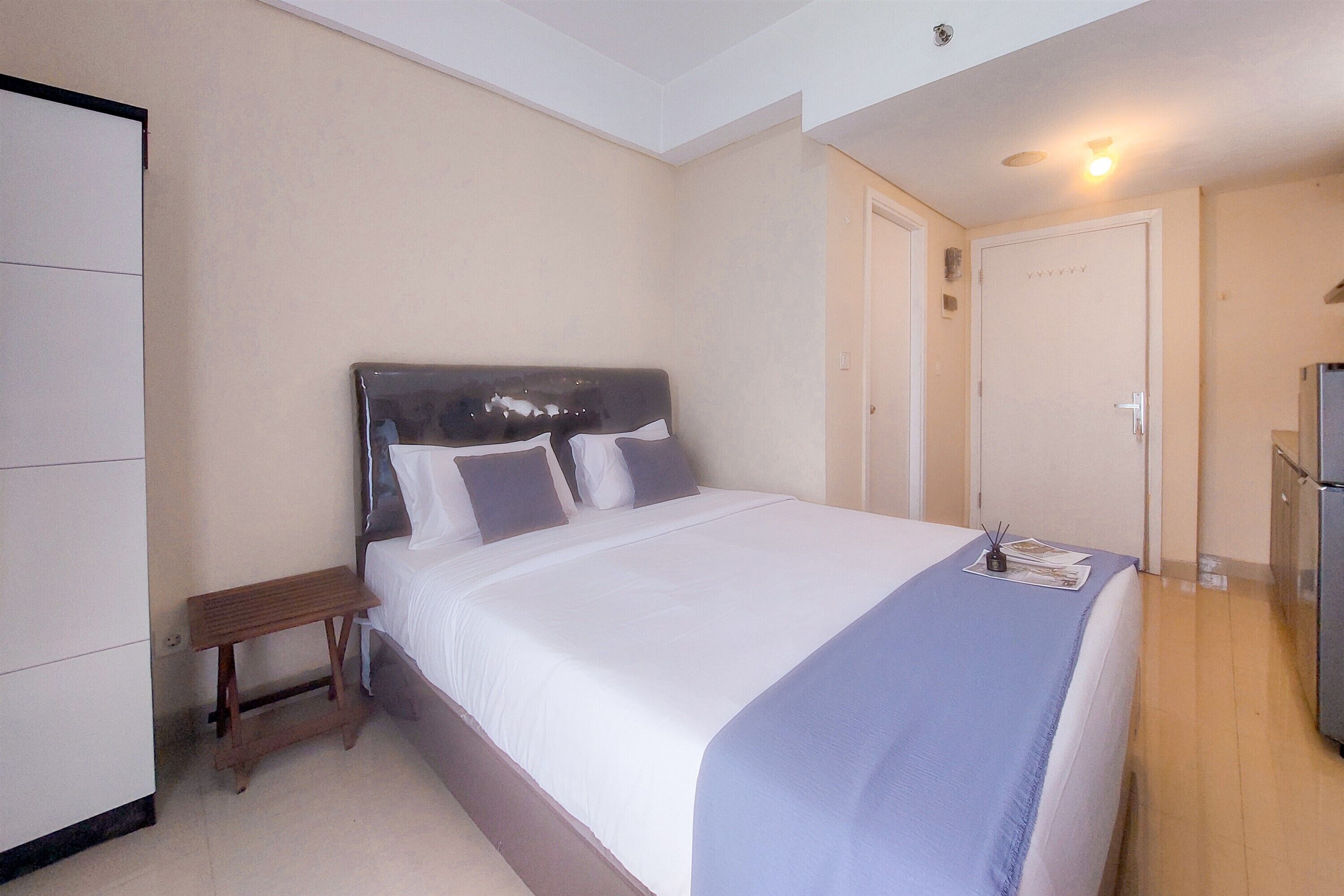 A neatly made bed with a headboard, a bedside table, and a small bench.