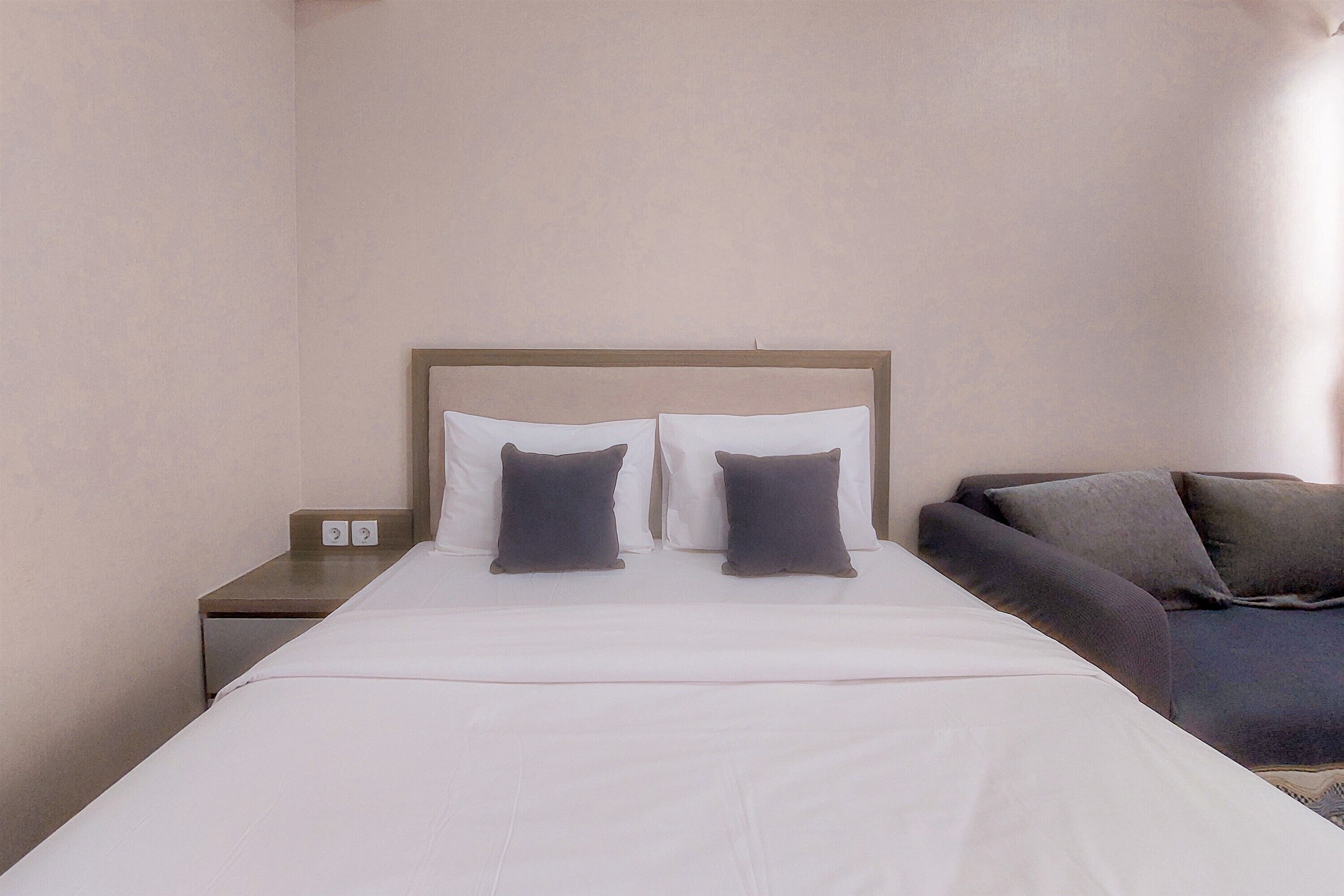 Una camera d'albergo con un letto, due cuscini, un comodino e una zona salotto.