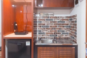 A compact kitchen with a brick backsplash, a sink, and a small refrigerator.