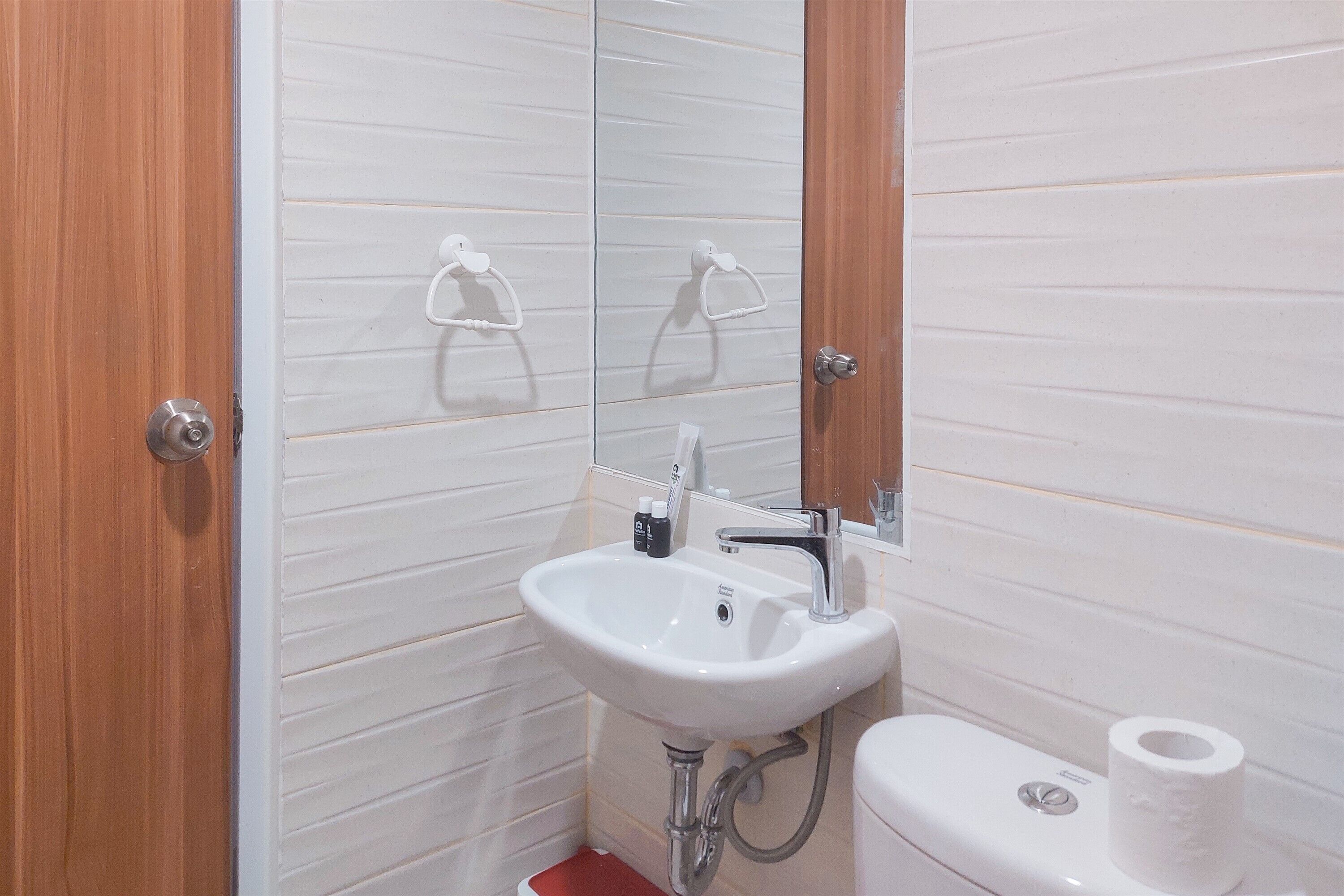 Et badeværelse med en hvid vask, et spejl og et toilet.