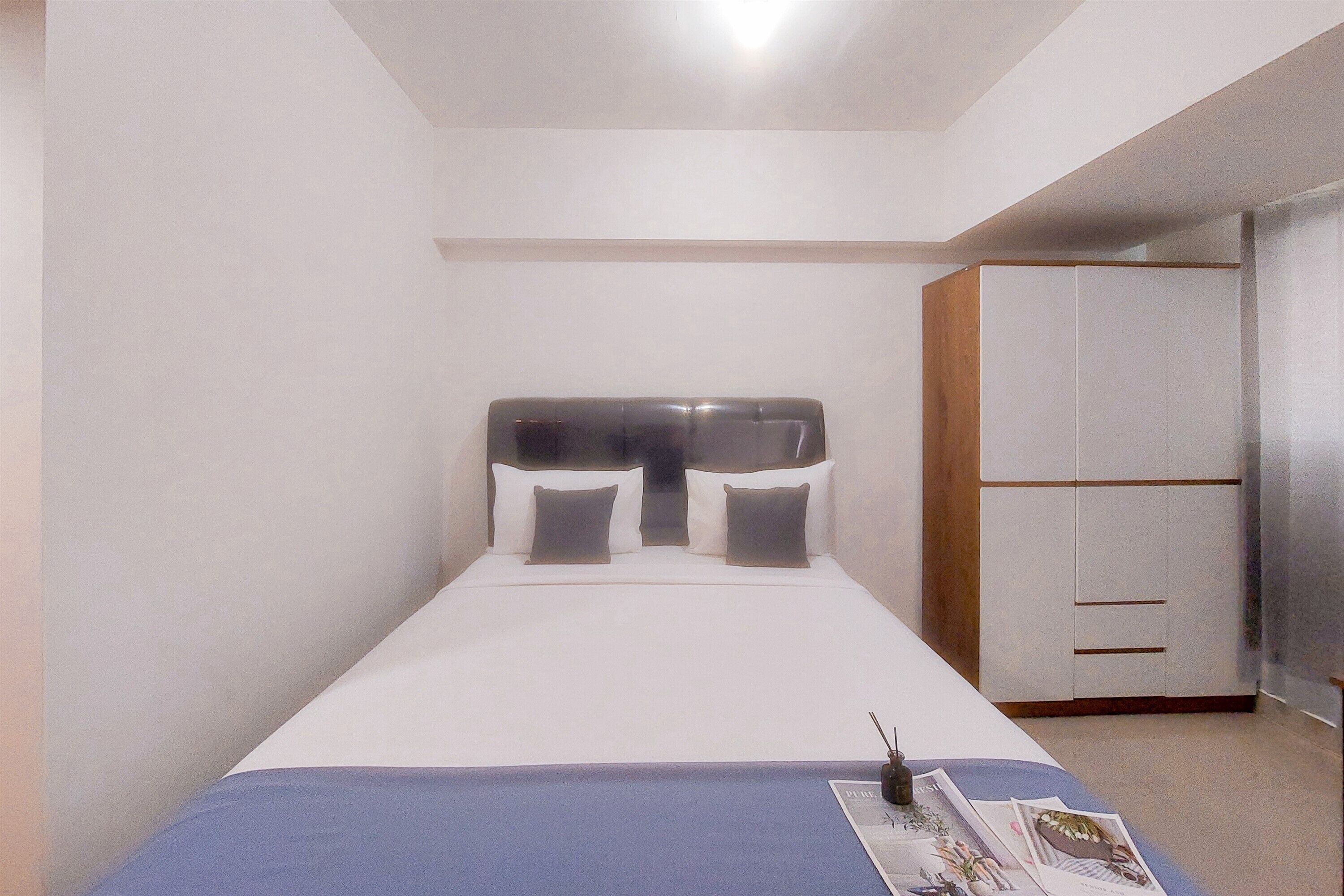 A bedroom with a bed, a wardrobe, and a bedside table with a magazine.