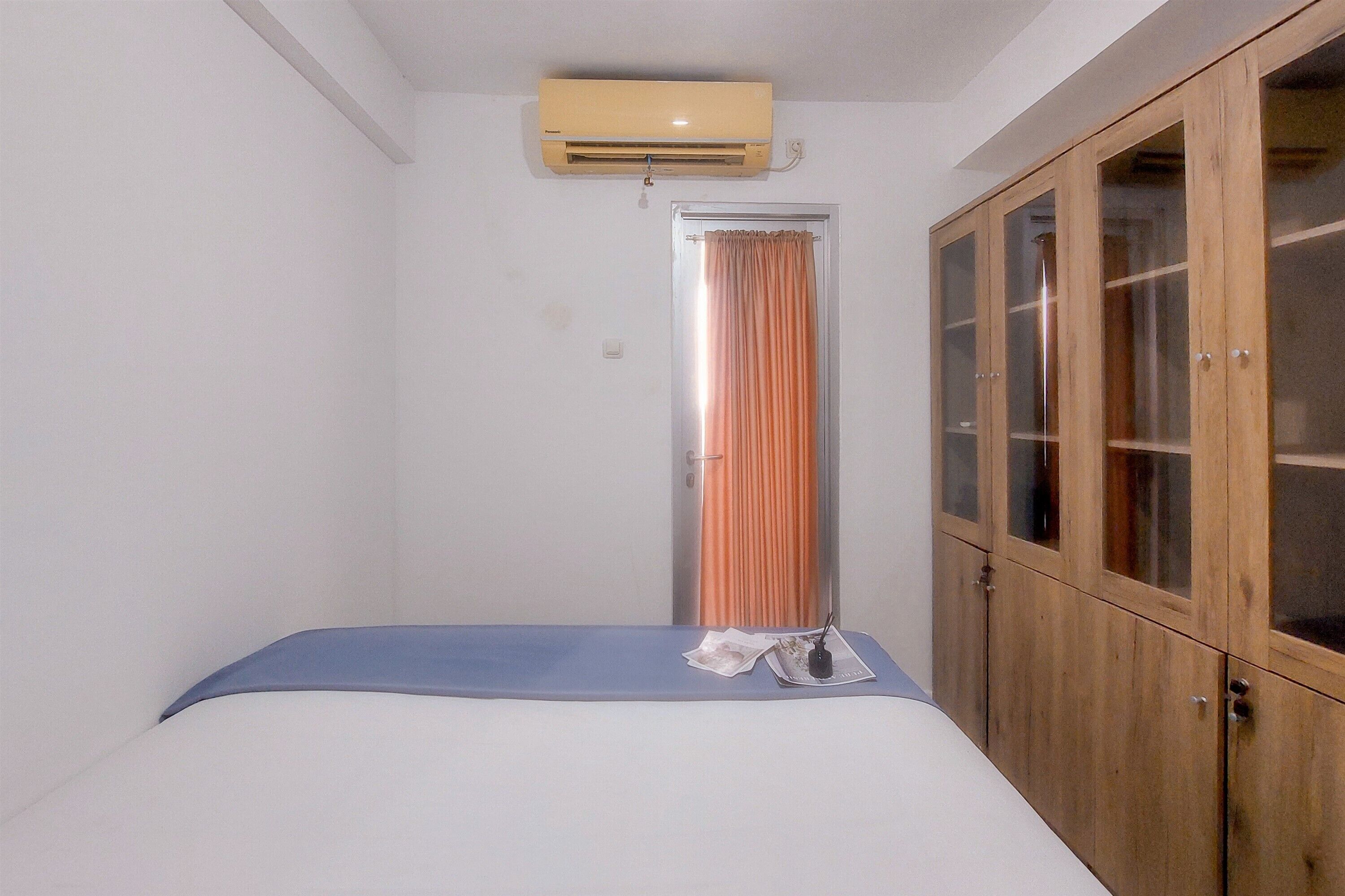 Un dormitorio con cama, aire acondicionado, armario y cortina.