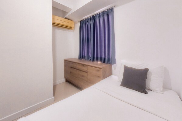 A bedroom with a bed, a wooden nightstand, a dresser, and a window with curtains. - Simply And Homey 2Br Urbantown Serpong Apartment (South Tangerang)