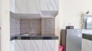 Eine moderne Küche mit Marmorfliesenspiegel, einem Edelstahl-Kühlschrank und einer Spüle.
