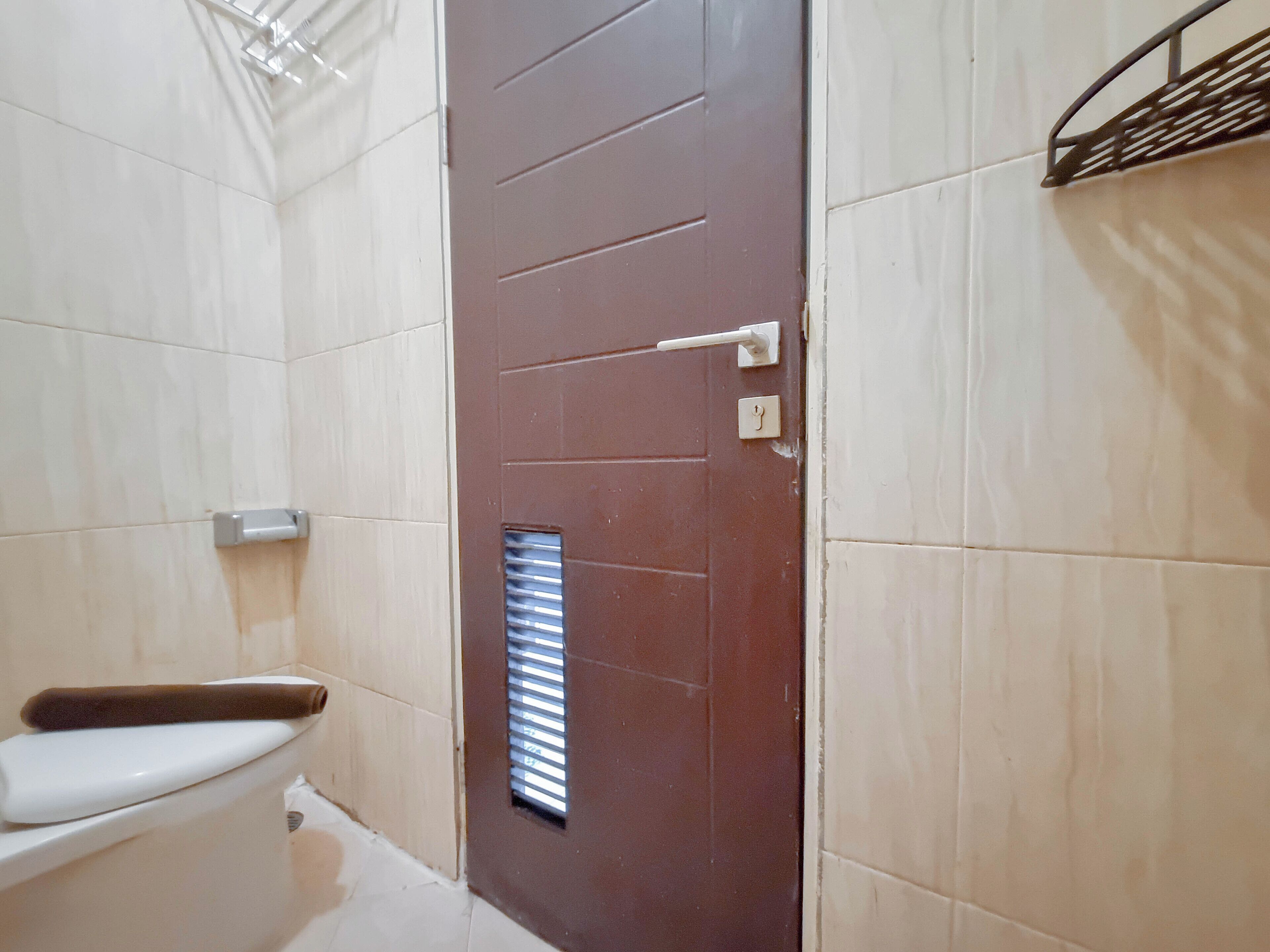 Baño con inodoro, toalla y puerta con ventanal.