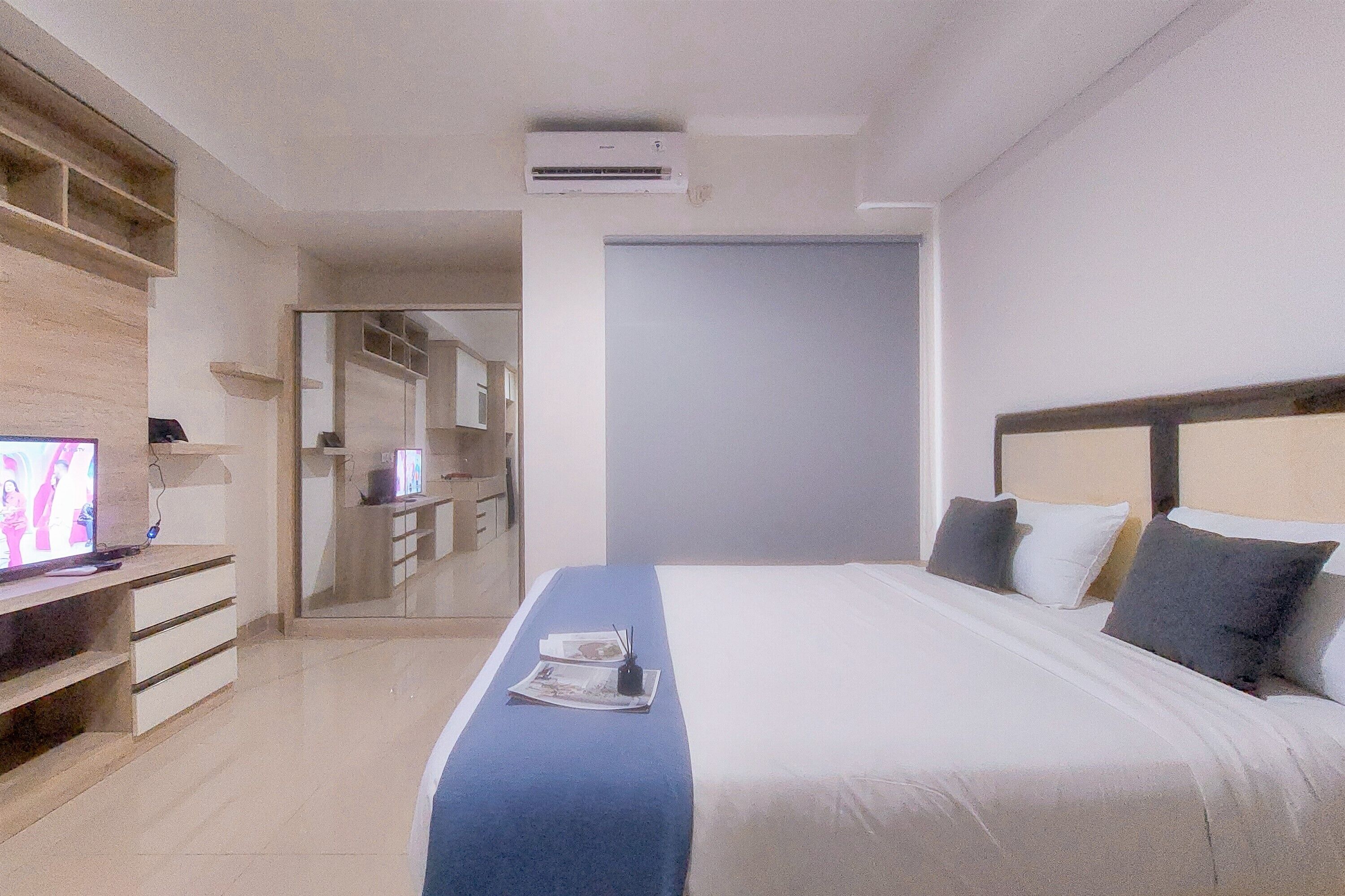 Una habitación de hotel con una cama, un televisor, un escritorio y un armario.
