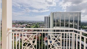 Un edificio alto con fachada de vidrio moderna, visto desde un balcón con barandillas blancas geométricas.