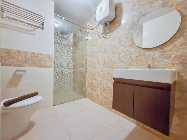 Un baño con ducha, inodoro, lavabo y espejo.