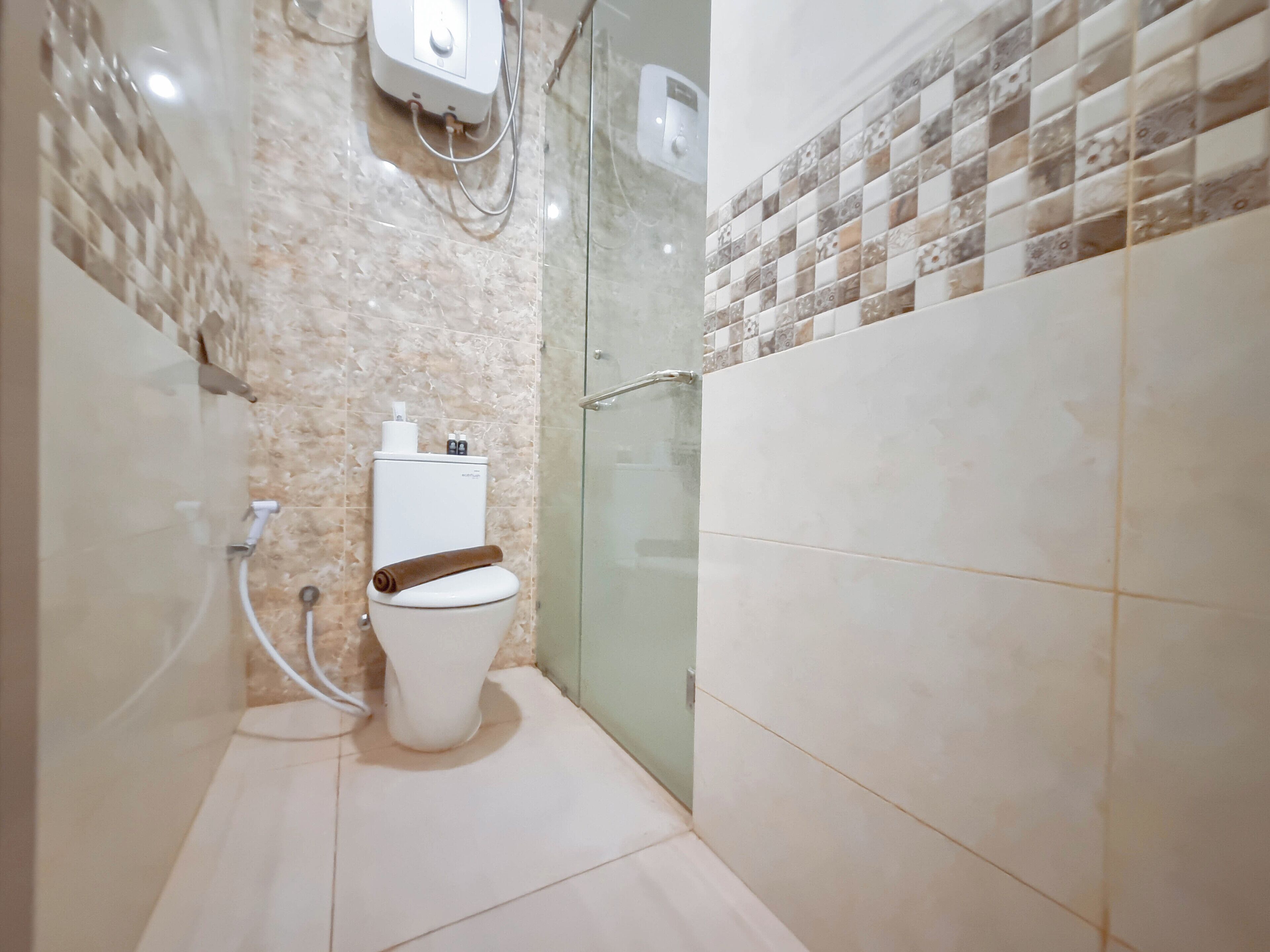 A bathroom with a toilet, a shower, and a glass-enclosed shower area.