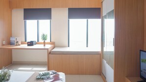 A modern office space with a wooden desk, a computer, and a window with blinds.
