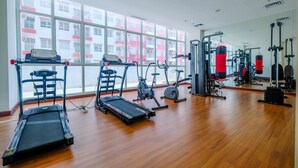 A gym with treadmills, elliptical machines, and weightlifting equipment. - Comfort Studio Taman Melati Margonda Apartment (Depok)