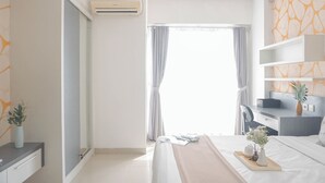 A modern hotel room with a bed, bedside table, and a window with curtains. - Comfort Studio Taman Melati Margonda Apartment (Depok)